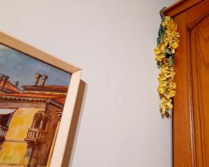 Une garrlande de fleurs jaunes sur un mur à côté d'un tableau dans l'établissement Casa Fiorina, à Barga