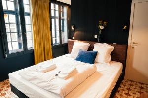 a large bed with white sheets and blue pillows at Gran Hotel De Passage in Bruges +136 photos