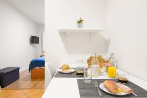 a table with two plates of food and orange juice at Porta 34 Apartments in Braga