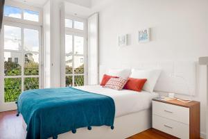 a white bedroom with a large bed with red pillows at Porta 34 Apartments in Braga