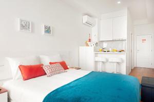 a white bed with red and blue pillows in a room at Porta 34 Apartments in Braga