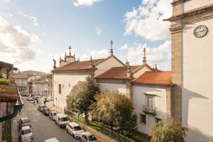 una strada cittadina con torre dell'orologio e auto parcheggiate di Porta 34 Apartments a Braga