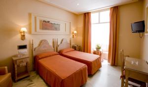 a hotel room with two beds and a tv at Los Helechos in Sanlúcar de Barrameda +30 photos