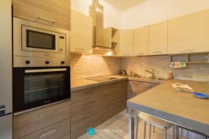 a kitchen with wooden cabinets and a microwave oven at MADREPERLA - SAN FOCA in San Foca