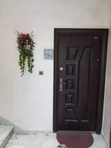 una porta marrone con composizione floreale su un muro di Cirta duplexe a Qusanṭīna (Costantina)