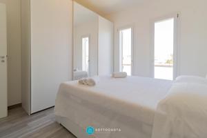 a white bedroom with a large bed with towels on it at MADREPERLA - SAN FOCA in San Foca