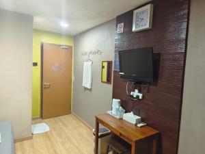 een kamer met een tv en een houten muur bij Hotel Ikhwan in Kota Bharu