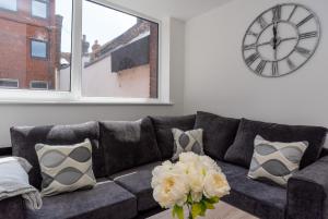 a living room with a couch with a clock on the wall at Bishops Lynn House Apartments - Town Centre in Kings Lynn