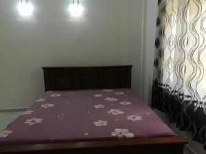 a bed with a purple comforter with flowers on it at Wood Land Villa in Ambalantota