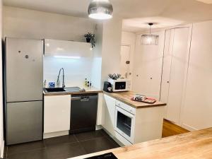 a small kitchen with a refrigerator and a sink at Loft66 avec parking privé in Clermont-Ferrand