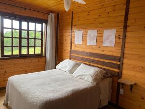 um quarto com uma cama num quarto de madeira em Cabanas Recanto do Rancho - Rancho Queimado em Rancho Queimado