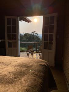 um quarto com uma cama e vista para uma varanda em Cabanas Recanto do Rancho - Rancho Queimado em Rancho Queimado