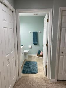 La salle de bains est pourvue de toilettes et d'un tapis bleu. dans l'établissement Sunset Retreat, à Bradenton