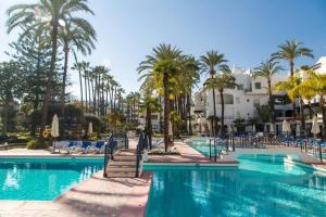 una piscina en un complejo con palmeras y sillas en Super Stylish apartment in La Alcazaba - RDR172, en Marbella