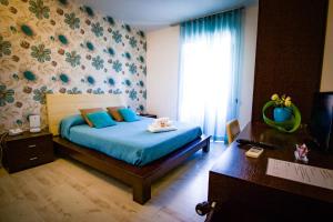 Schlafzimmer mit einem Bett mit blauer Bettwäsche und einem Fenster in der Unterkunft Abraxia B&B in Comiso