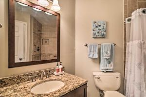 a bathroom with a sink and a toilet and a mirror at St Pete Condo with Private Lanai and Community Pool! in St Petersburg