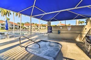 a hot tub on a deck with a blue umbrella at St Pete Condo with Private Lanai and Community Pool! in St Petersburg