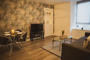 a living room with a couch and a table and a television at 1 bedroom flat with easy parking/public transport in Dundee