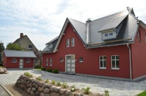 ein rotes Haus mit einer steinernen Einfahrt in der Unterkunft Landhaus Hagenblick - Apt. 02 in Alt Reddevitz