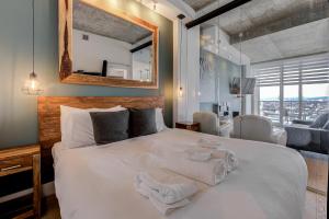 1 dormitorio con 1 cama blanca grande y toallas. en Les Immeubles Charlevoix - Le 760631, en Quebec