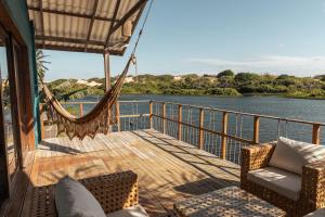 a hammock on a deck with a view of the water at Casa na Lagoa in Paracuru