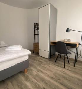 a bedroom with a bed and a desk and a chair at Apartamenty Zatorze in Leszno