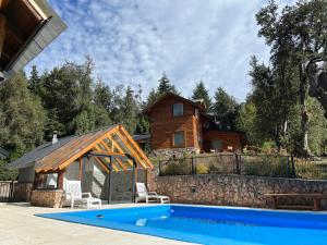 uma casa com piscina em frente a uma casa em Portal del Manzano em Villa La Angostura