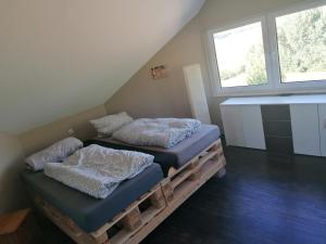 2 Betten auf einer hölzernen Plattform in einem Zimmer mit Fenster in der Unterkunft Ferienwohnung mit Charme in Bad Salzschlirf