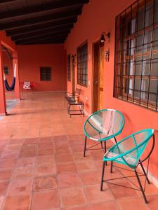 un patio con 2 sillas y una pared roja en La Casa de Cafe Bed and Breakfast, en Copan Ruinas