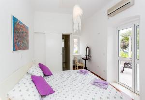 a white bedroom with a large bed with purple pillows at Villa Marini Dvori - with free parking in Dubrovnik