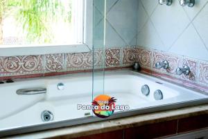 a bath tub in a bathroom with a window at Pousada Ponta do Lago in Florianópolis