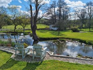 two chairs sitting in front of a pond at Riverside Cabin at Pen-Y-Bont Mill in Oswestry