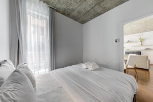 um quarto com uma cama branca e uma grande janela em Les Immeubles Charlevoix - Le 760207 em Cidade de Quebec