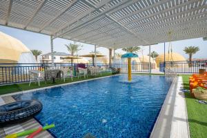 a swimming pool with an umbrella and chairs and a swimming pool at Camp Sahara in Kalia