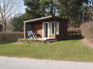 a small cabin with a chair in the grass at First Camp Aarhus - Jylland in Aarhus