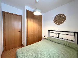 1 dormitorio con cama verde y puerta de madera en Apartament La Gisca, en Valencia de Aneu