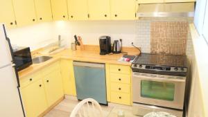 een kleine keuken met gele kasten en een fornuis bij Applewood Gardens Apartment in Mississauga