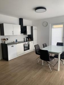 ヒルシャイトにある3 Zimmer Ferienwohnung Hannaの白いキャビネット、テーブルと椅子付きのキッチンが備わります。