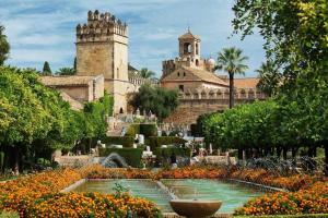 a garden with a fountain in front of a castle at Boabdil Suites in Córdoba