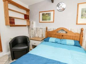 a bedroom with a bed and a chair and a clock at The Nook in Llanfyrnach