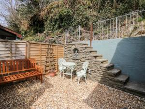 a patio with a table and chairs and a stone wall at The Nook in Llanfyrnach