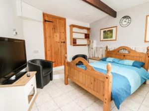 a bedroom with a bed and a flat screen tv at The Nook in Llanfyrnach