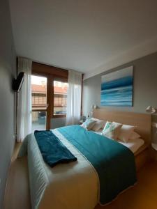 a bedroom with a large bed with a large window at Apartamento Playa de Barro in Barro de Llanes