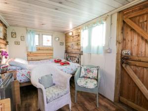 a bedroom with a bed and a chair in a room at Ketburn Shepherds Hut at Balnab Farm in Newton Stewart