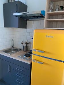 a yellow refrigerator in a kitchen with a sink at Ferienwohnung am Südstrand auf Fehmarn, Hafenblick in Fehmarn