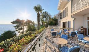 a patio with tables and chairs and the ocean at Hotel Stanger in Lovran