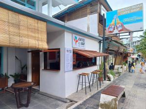 a building with tables and stools outside of it at Komodo Indah Hotel and Hostel in Labuan Bajo