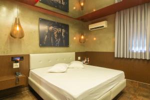 een slaapkamer met een groot bed met witte lakens bij Opium Motel (Adult Only) in Sao Paulo
