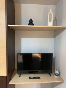 a television on a shelf with a remote control at hommie apartment in Amalias