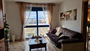 uma sala de estar com um sofá e uma grande janela em Appartement vue mer près de la plage et centre ville em Vinarós